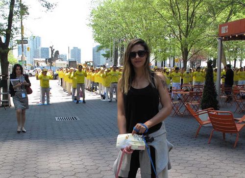 图13：五月十二日，在纽约生活的以色列女孩罗密在达格•哈玛绍广场公园被法轮功学员的集体炼功场面所吸引，赞美法轮功的平和力量。