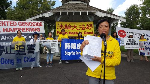 法轮功学员代表刘女士向公众展示九千份征集到的声援“诉江”的签名表。