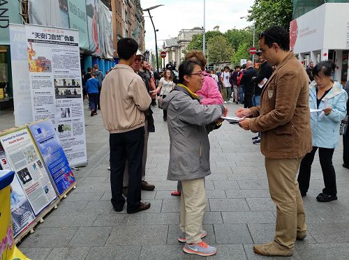 图1-2：七月三十日，爱尔兰学员在都柏林的格拉夫顿大街上传播法轮功的真相，民众了解中共的罪恶后，联署举报迫害法轮功的元凶江泽民。