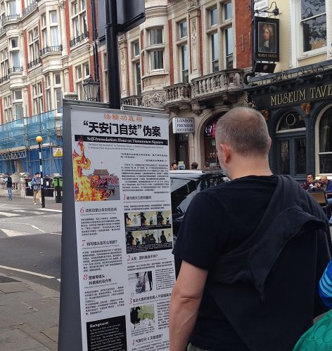 图2：游客驻足观看阅读摆在大英博物馆门前人行道旁的法轮功真相展板