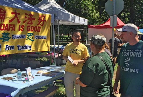 '图：伊利诺伊州中部的法轮功学员在菊花节上设立展位，向民众传播法轮功的真相，并征集签名制止活摘。'