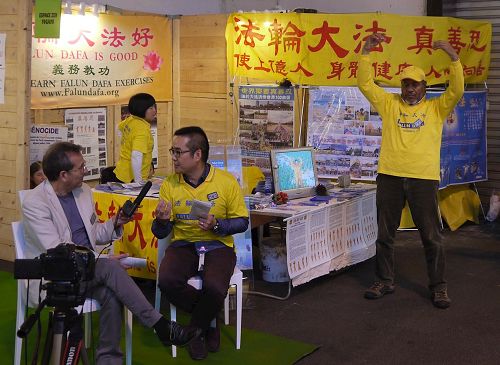 '图4:展会期间,主办方记者来到法轮功展位进行了录像并采访了法轮功学员,采访内容将刊登在主办方的网站、脸书、推特等相关网页上。'