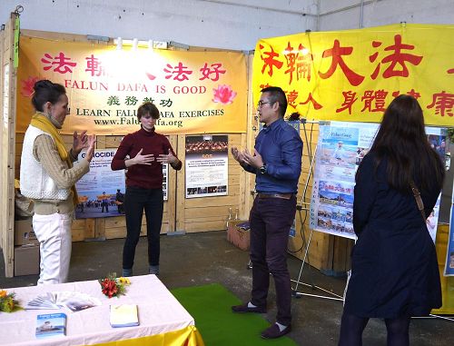 '图5:Dipankara(左)和她的朋友(中)一起在展会上学炼法轮功五套功法。'