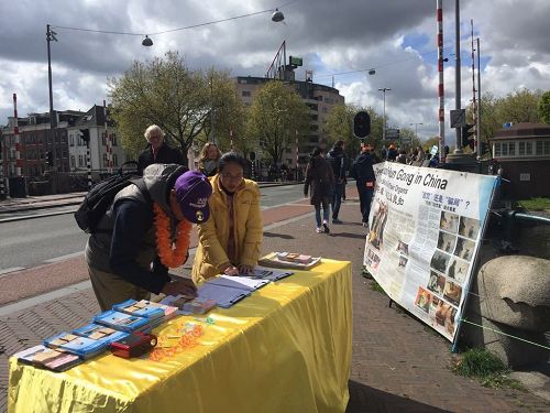 '图1：法轮功学员在阿姆斯特丹举办讲真相活动，民众签名支持反迫害'