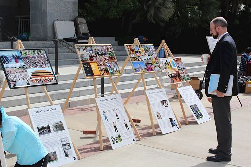 '图4:这位男士专注阅读真相展板上的照片和介绍法轮功的内容。'