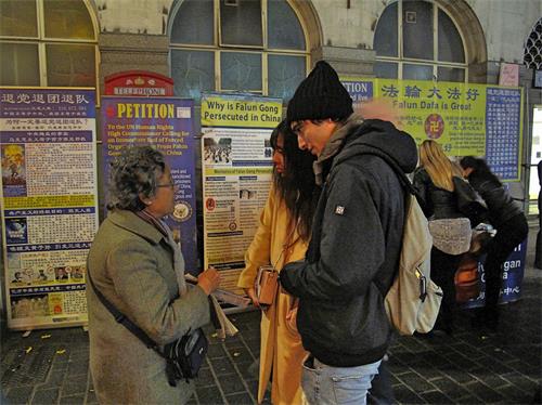 '图8：十一月十七日，两位意大利游客在伦敦唐人街第一次听说法轮功，了解真相后立即签名反迫害。'