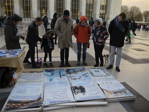 '图1～2：二零一八年十二月九日下午，在巴黎人权广场，游人阅读法轮功真相展板'