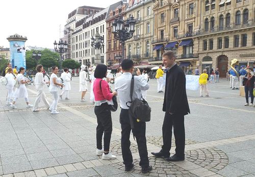 图2：法轮功学员的游行队伍吸引大陆游客驻足观看并摄影。这位西方学员（右侧深衣者）在用流利的中文给他们讲真相。