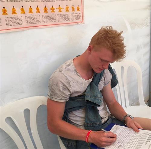 '图8：学生哈斯穆斯（Rasmus）在反迫害征签表上签名'