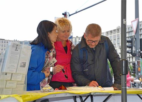 '图4：一对来自瑞典的游客在征签簿上签字支持反迫害'