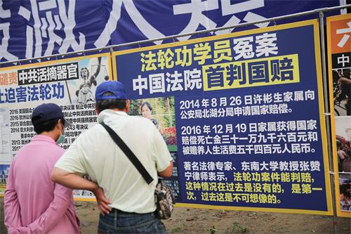 '图11：来自台南西港的市民郭先生夫妇第一次遇到法轮功，沿着真相展板一片片非常仔细的阅读着，并呼吁公安明智抉择。'