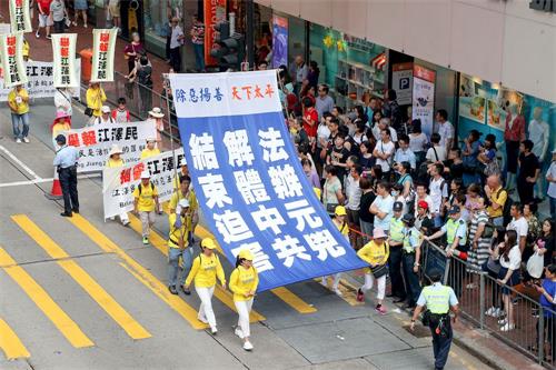 '图9～18：约一千名法轮功学员7月22日在港岛区举行反迫害十九周年集会游行，呼吁停止迫害、法办元凶。游行队伍中大小横幅展示中共迫害法轮功的真相，震撼许多大陆游客。'