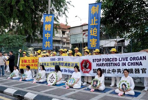 '图1～2：2018年7月20日，马来西亚法轮功学员来到中共使馆，在车水马龙的大路旁举行集会，悼念被中共迫害致死的法轮功学员。'