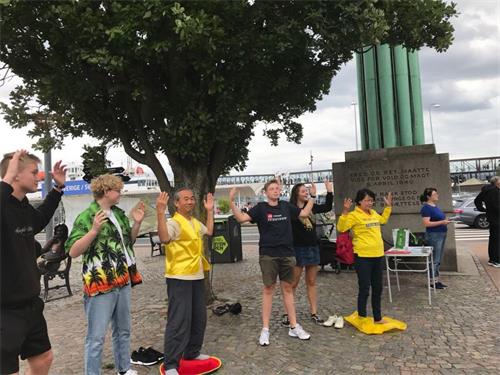 '图：一群赫尔辛格青年在象征和平和正义的“瑞典柱”Sveas?jlen塔旁学炼法轮功。'