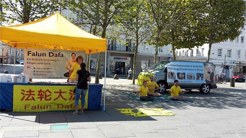 '图：二零一八年八月十七日，法轮功学员在奥地利南部克恩顿州（Kärnten）的首府克拉根福特（Klagenfurt）市政厅前“新广场”上，设立真相点，向过往民众传播法轮功的真相。'