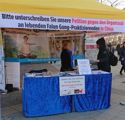 '图1～2：二零一九年十二月十日国际人权日这一天，人们在德国汉诺威的法轮大法信息展位前了解情况，并签署反对中共活摘器官的请愿书。'