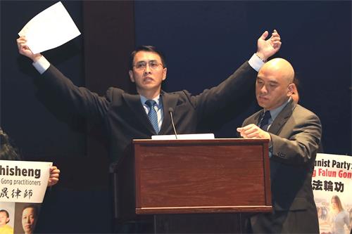 '图2:法轮功学员于溟在新闻发布会上演示中共监狱的“吊铐”酷刑,他曾被这一酷刑持续折磨长达一个月。'