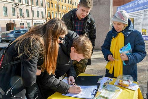 '图1：俄罗斯圣彼得堡市中心，路人签名支持法轮功学员反迫害。'