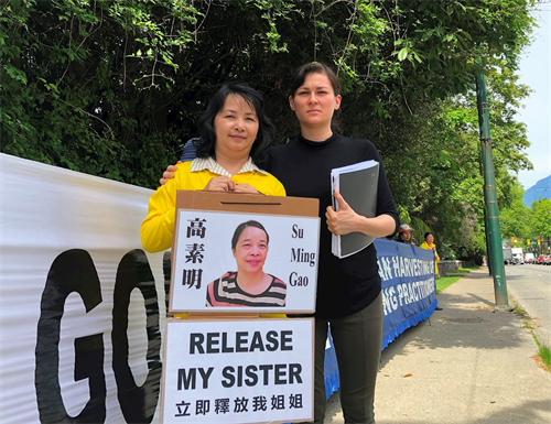 '图：高俏明（左）拿着姐姐高素明的照片站在横幅前，温哥华妇女人权组织的Lin女士（右）对高素明的境况表示关切。'