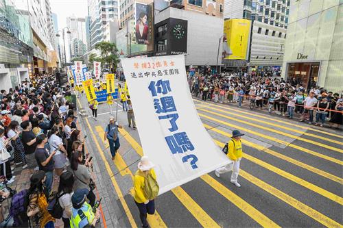 '图11：法轮功学员举起大型幡旗，呼吁大陆民众退出中共党团队。'