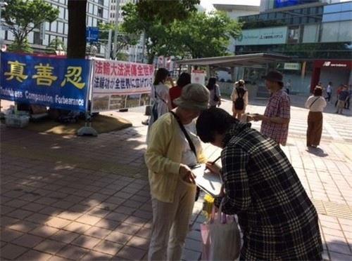 '图1～2：法轮功学员在日本爱知县首府名古屋市举办活动讲真相，庆祝世界法轮大法日。民众明真相后，签名声援法轮功。'