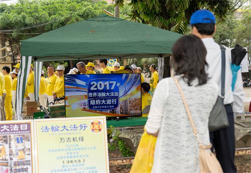 图5～6：2019年5月5日，在高雄桥头糖厂提前庆祝“世界法轮大法日”，民众驻足观看法轮大法洪传世界图片展和电视影片。