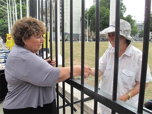 '图13：“反迫害二十周年”， 法轮功学员在英议会大厦外展示真相，其中有对中共在大陆对法轮功学员非法关押监禁和残酷迫害的模拟，英国会议员玛丽·里默（Marie Rimmer MP）到场支持法轮功学员反迫害'