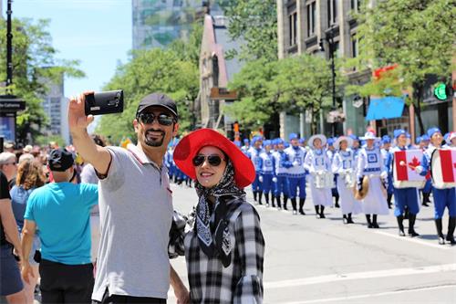'图9：蒙特利尔居民Zeinab女士（右）表示十分喜欢法轮大法的游行队伍。'
