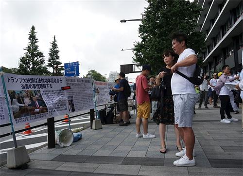 '图6～7：日本法轮功学员在东京九段下车站摆展板，讲真相，民众驻足阅读展板。'
