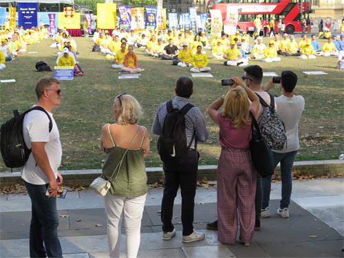 图1～3：法轮功学员在伦敦议会广场花园集体大炼功吸引了许多人观看。