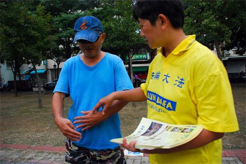 '图8：文化公园里，一位市民认真观看功法展示，他现场学功，后来还参加了九天学法炼功班。'