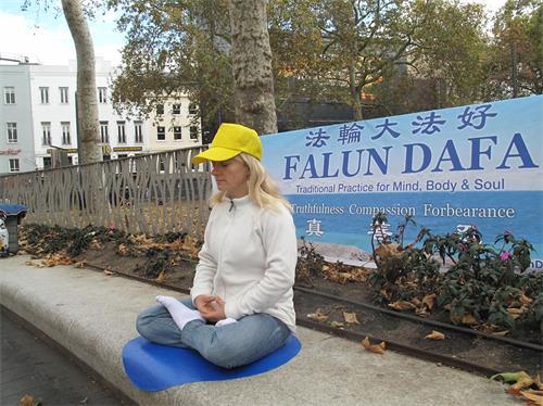 '图6：二零一九年九月一日，瑞士法轮功学员丹尼丝（Denise）在伦敦莱斯特广场展示法轮功功法'