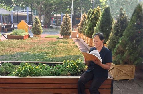 '图：小玉正在阅读法轮大法创始人李洪志大师的专著《转法轮》'