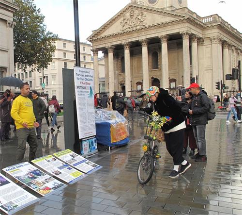 '图9：二零二零年十月十日，英国威尔士女士简（Jane）在伦敦特拉法加广场逐幅认真阅读法轮功真相展板'