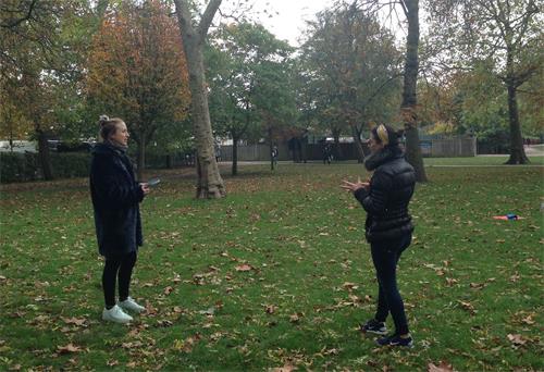 '图1：二零二零年十月十八日，法轮功学员卡瑞娜（Carina）在伦敦女王公园（Queen's Park）炼功打坐后与不期而遇的瑜伽老师珍妮（Jenny）轻松交谈'