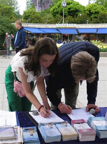 '图6：五月九日，挪威民众在在一份呼吁挪威国会和政府帮助制止中共活体摘取法轮功学员器官的呼吁书上签名'