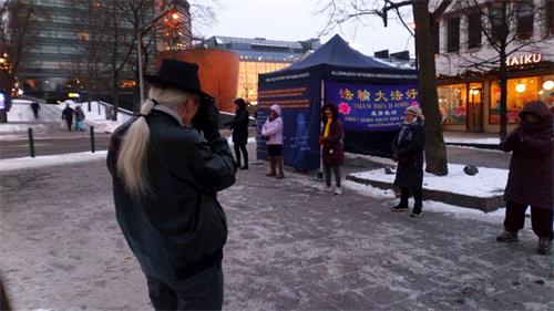'图1～2：二零二一年一月九日，芬兰法轮功学员来到首都赫尔辛基甘比（Kampi）购物中心附近的广场上，设立真相点。图为法轮功学员正在演示功法。'