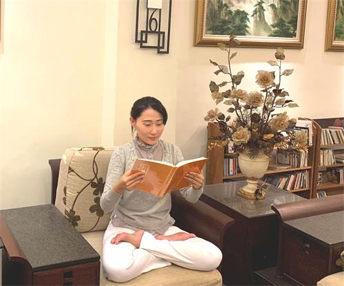 '图1：王郁青老师从《转法轮》一书中重新拥有焕然一新的人生。图为她正在阅读《转法轮》。'