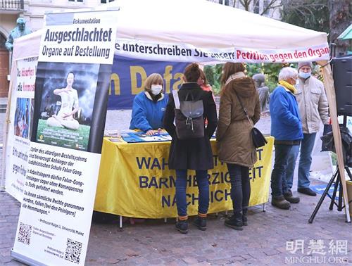 '图1～2：二零二一年十二月十一日，法轮功学员在德国海德堡老城本生广场（Bunsenplatz）举办活动，讲述法轮功反迫害真相，揭露中共活摘器官的罪恶。'