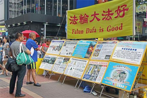 '图6～7：香港街头讲真相的法轮功学员无所畏惧，风雨无阻的传递真相，从未停歇。'