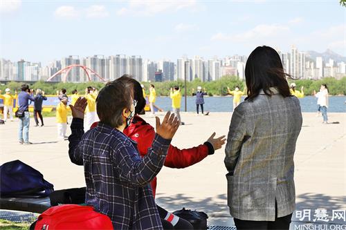 图20:首尔市民们在观看汝矣岛汉江公园法轮功学员集体炼功，并跟随学习
