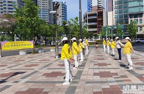 图23:韩国蔚山学员在乐天百货公司北广场集体炼功洪法庆祝世界法轮大法日。