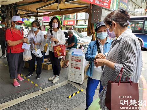 '图1:法轮功学员在传统市场出入门口设摊协助单位执行实联制,并讲真相及送上带有真善忍信息的莲花与真相资料。'