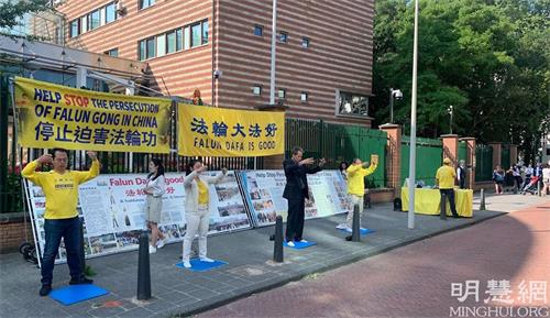 '图6～7：法轮功学员在中共大使馆前面对前来排队的华人讲真相，并集体炼功'