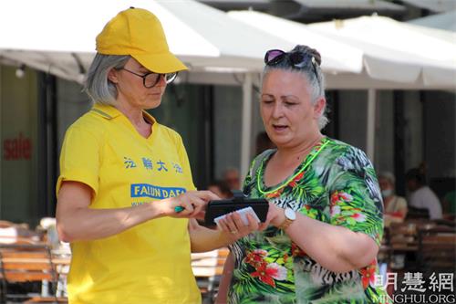'图7：法蒂玛（Fatma，右）看到法轮功学员在瑞士苏黎世市中心阅兵广场的活动，她提早下电车。她很高兴从学员那了解了炼功点的详细讯息。'