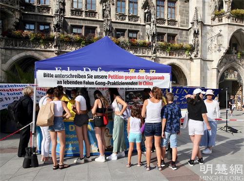 '图1：二零二一年八月十日，德国法轮功学员在慕尼黑玛琳广场（Marienplatz）举办活动。图为民众排队签名声援法轮功学员反迫害。'