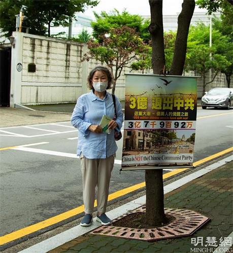 '图1：驻釜山中国总领事馆对面，南女士每天在固定的地点挂好真相横幅，向中国人发放真相资料。'