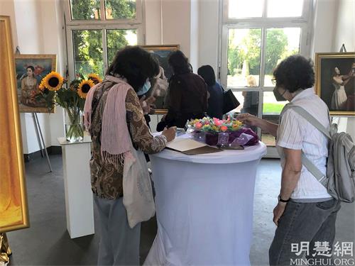 '图2：一位参观者在美展留言簿上留言。'