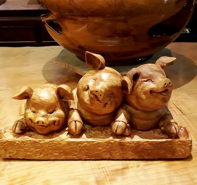 '图4：蔡明峰木雕作品山猪，憨态可爱又可喜。对于这件作品，他表示：“用三只小猪不同的表情来表现小时候无论是兄弟、姐妹、同学邻居、还是朋友之间的玩耍打闹情景，那是一种没有恩怨情仇的天真无邪和善良。”'