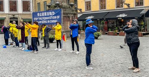 图6：明白了真相的民众（右一）对功法感兴趣，当场学炼法轮功。
